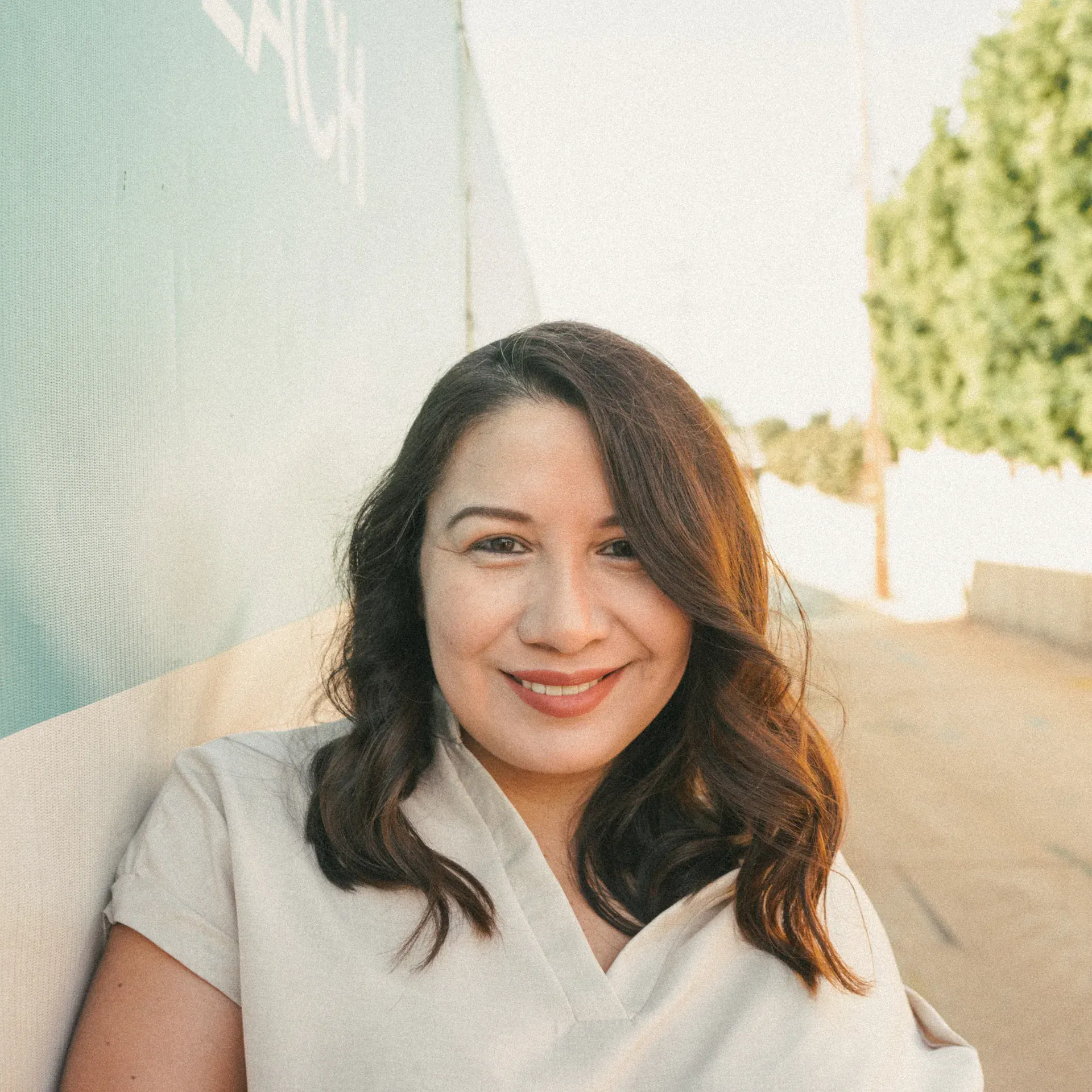 Sofia Mendoza smiles warmly on an urban street in a white top.