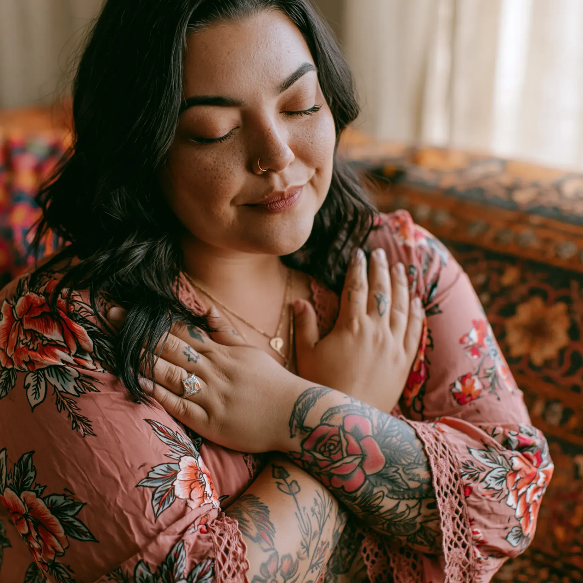 A woman meditates outdoors with her hands pressed together, mountains behind her