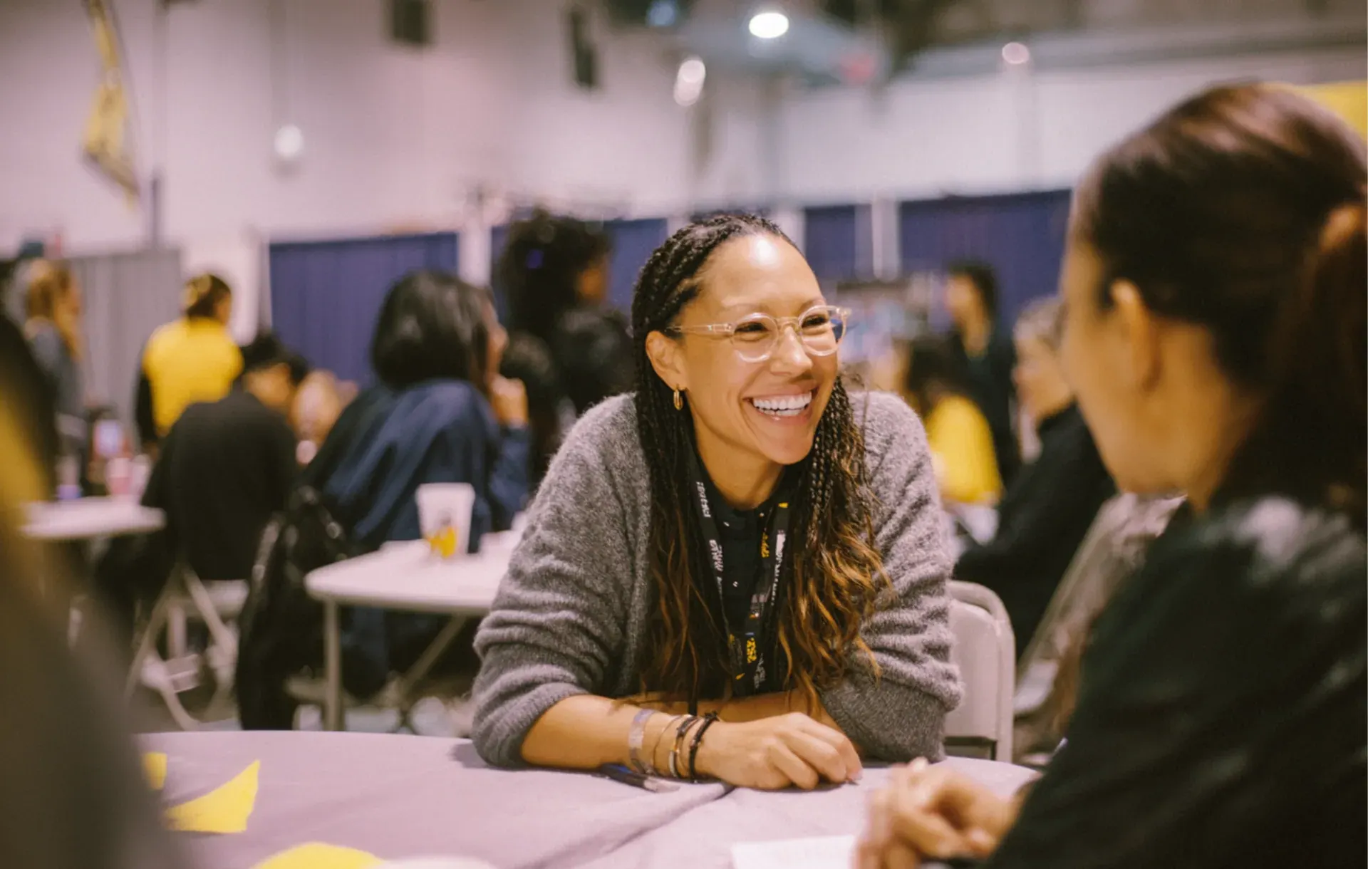 Two women talk closely at a table during a crowded community workshop