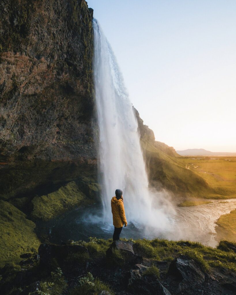 Person standing on rock near waterfalls